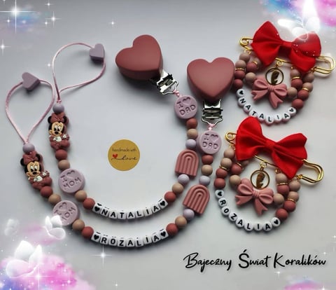 Two pink and mauve beaded pacifier clips with heart-shaped toppers, red bows, and personalized name charms arranged on a sparkly background